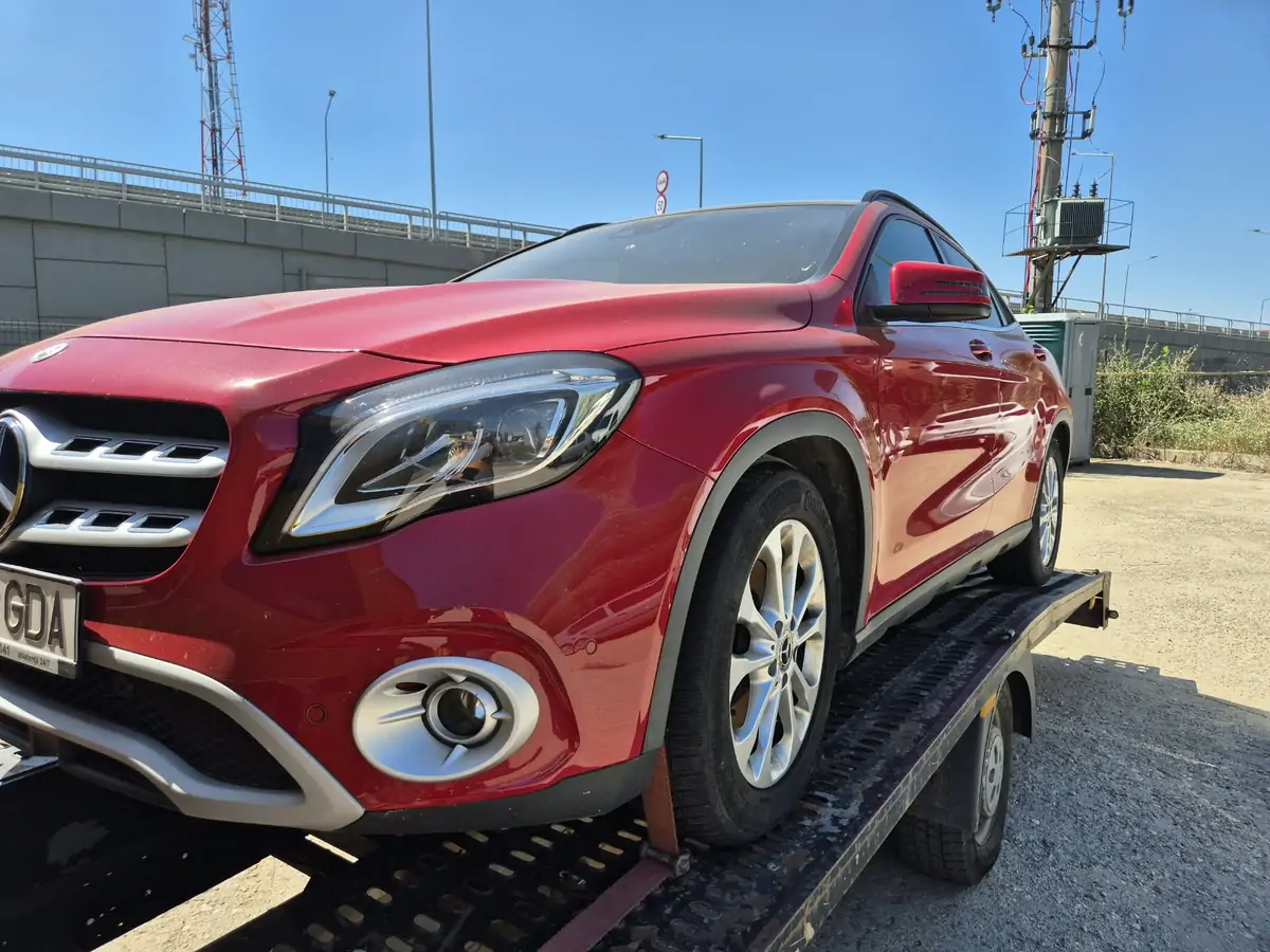 Mercedes roșu încărcat pe platforma auto galbenă
