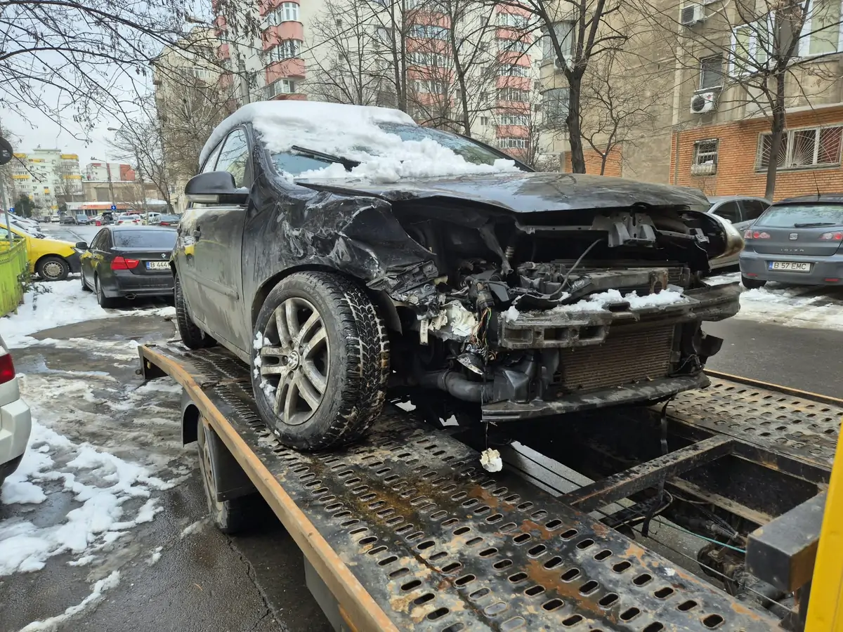 Mașină avariată tractată iarna, pe zăpadă