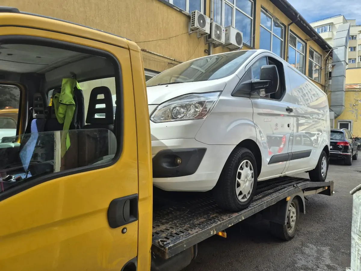 Autoutilitară albă transportată pe platformă