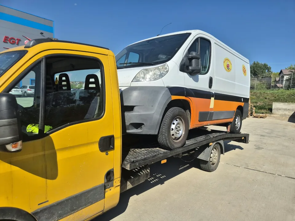 Autoutilitară albă transportată pe platformă auto